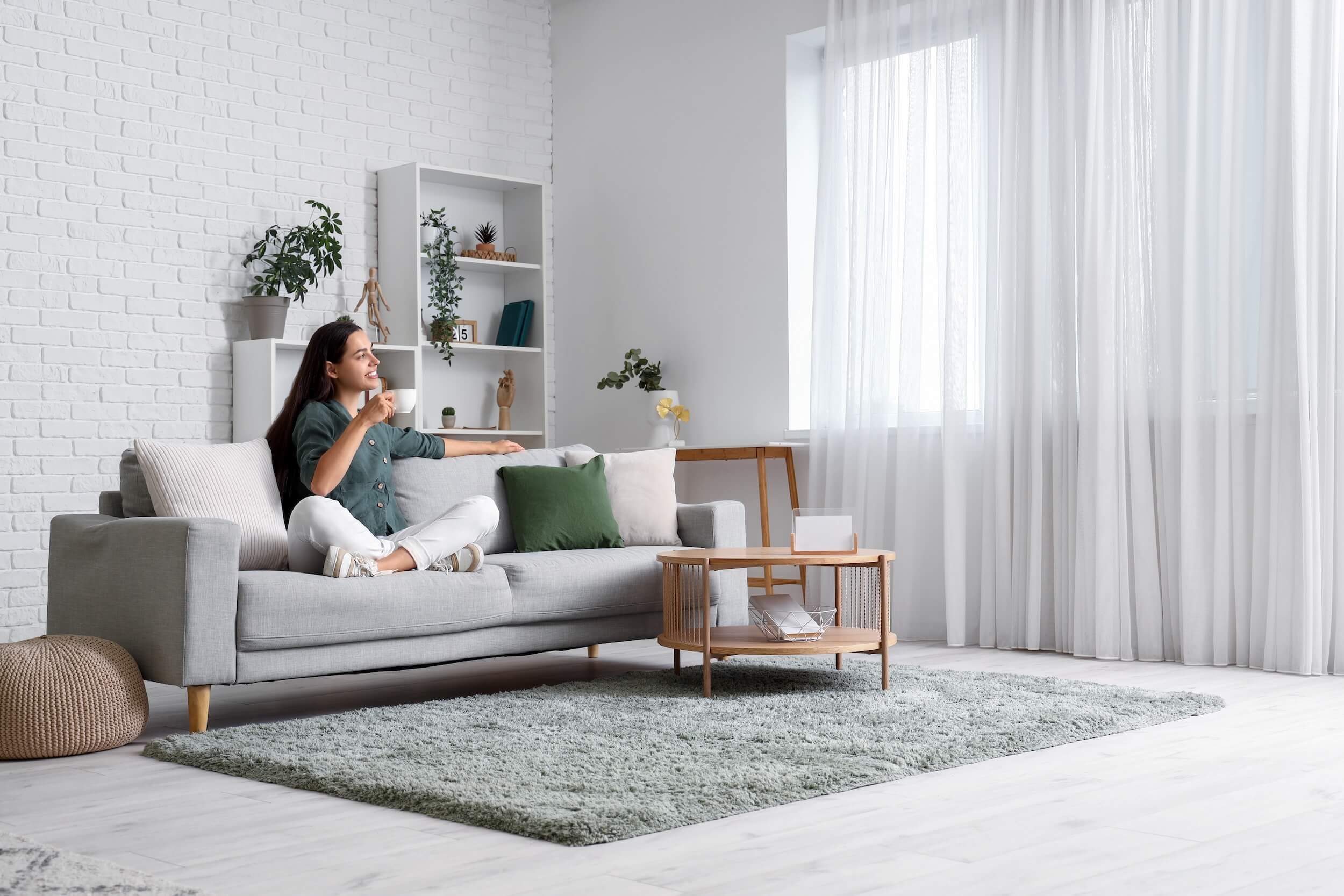 woman drinking coffee seated in white living room interior with natural light and various textures